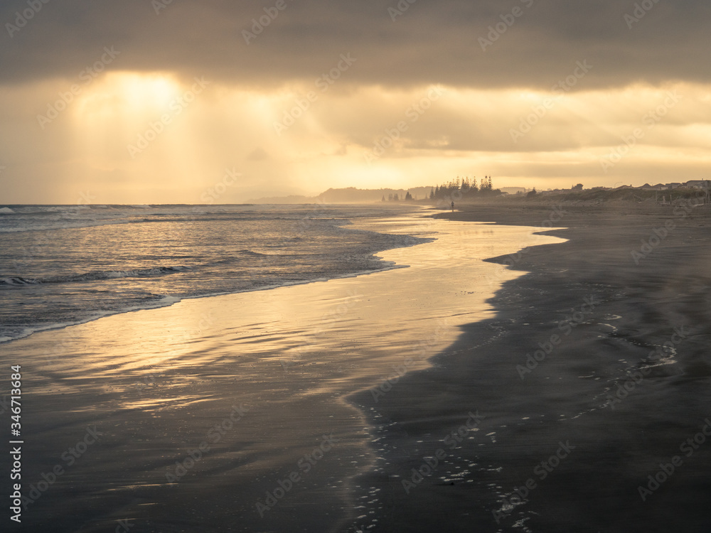sun rays poking through clouds over ocean beach