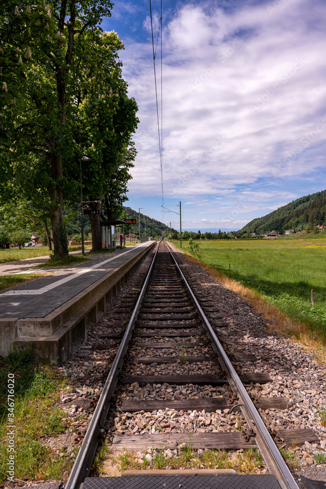 View along a small platform with railway tracks in the Black Forest in front of a beautiful landscape