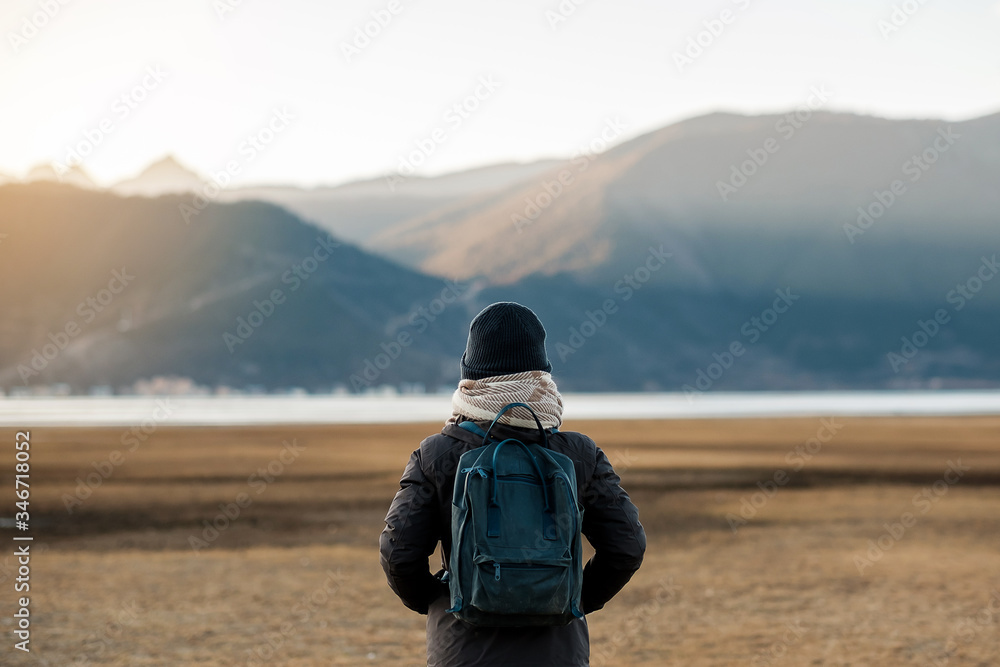 Hipster woman traveler with sweater and backpack traveling at Napa Lake, Happy young Hiker looking mountain and sunset in trip Shangri-La,Yunnan,China. Explore, Adventure and Asia Solo travel concept