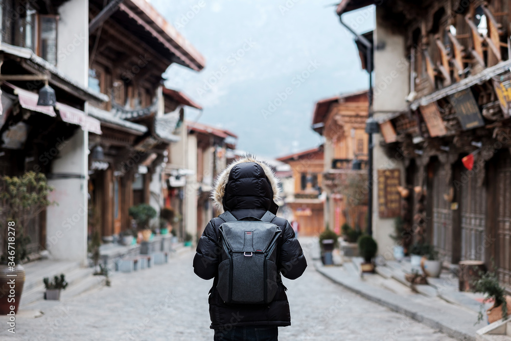 Young man traveler with sweater traveling in Dukezong old town, located in Zhongdian city (Shangri-La).landmark and popular spot for tourists attractions. Yunnan, China. Asia and Solo travel concept