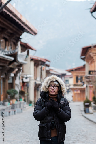 Young man traveler with sweater traveling in Dukezong old town, located in Zhongdian city (Shangri-La).landmark and popular spot for tourists attractions. Yunnan, China. Asia and Solo travel concept