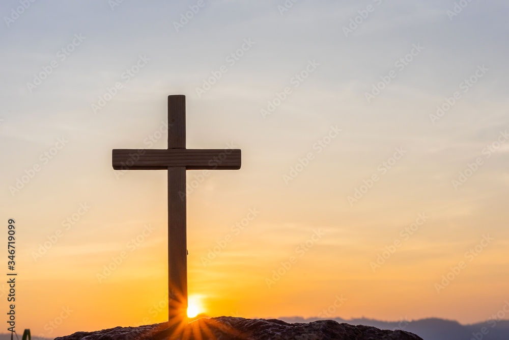 Silhouettes of crucifix symbol with bright sunbeam on the colorful sky background