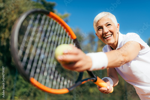 Senior Tennis – Pretty Mature Woman Serving Ball in Tennis © Microgen