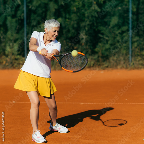 Positive Active Mature Woman Having a Tennis Lesson © Microgen
