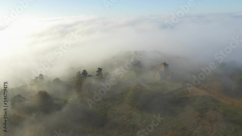 4k Aerial shot of a church in a foggy/cloudy forest on a mountain.
