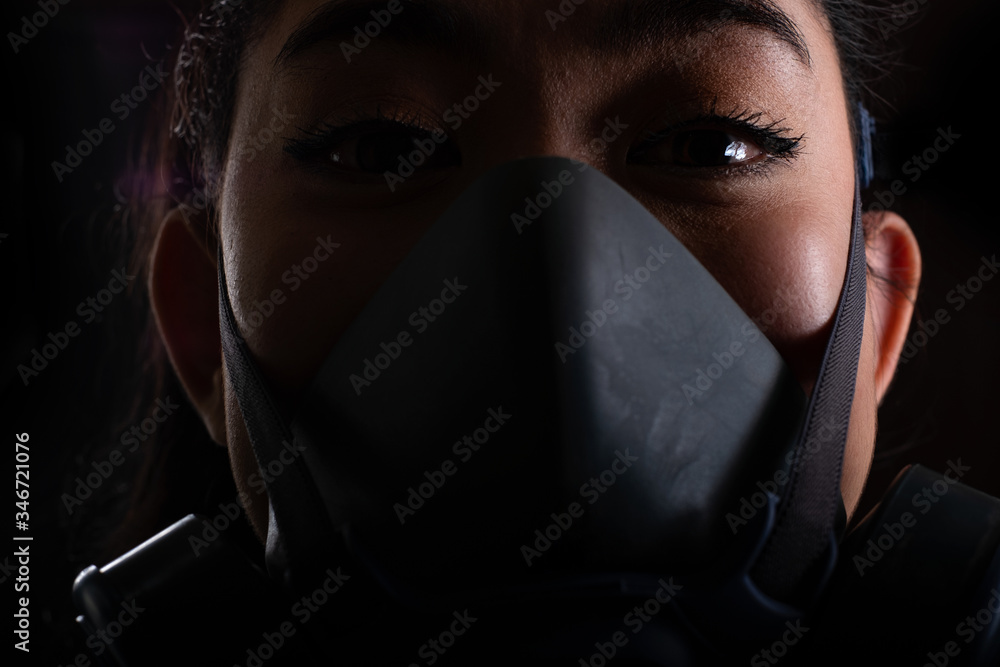 Close up the woman of young Asia woman putting on a Half-Mask replaceable particulate filter respirator to protect from airborne diseases as the chemical dust and smog