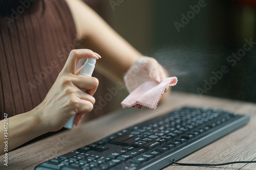 Woman hand desinfecting devices at home for prevent disease by sanitazing keybord, corona virus or Covid-19 protection. photo