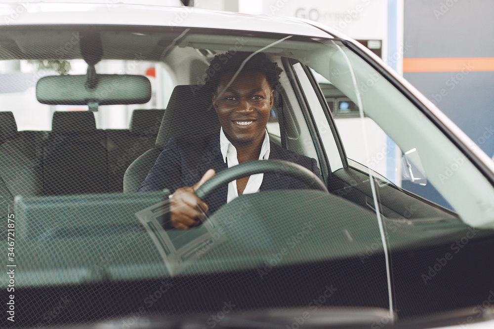 Man buying the car. Businessman in a car salon. Black male in a suit. Man buying the car. Businessman in a car salon. Black male in a suit.