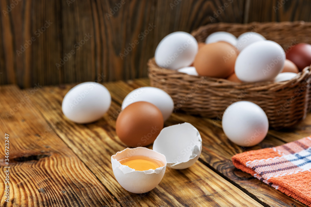 Farm eggs white and brown lie on a wooden table and in a basket, close-up, low light, selective focus, shallow depth of field. Organic food concept Farm eggs white and brown lie on a wooden table and in a basket, close-up, low light, selective focus, shallow depth of field. Organic food concept