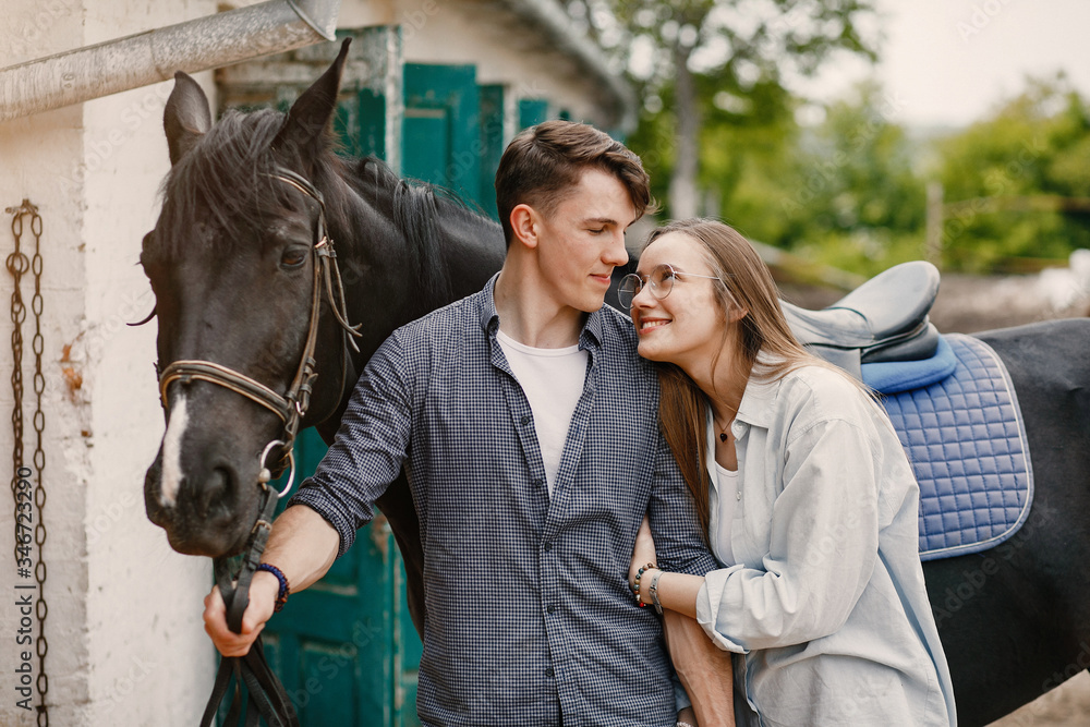 Couple on a ranch. Pair standing with a horse. Girl with her boyfriend