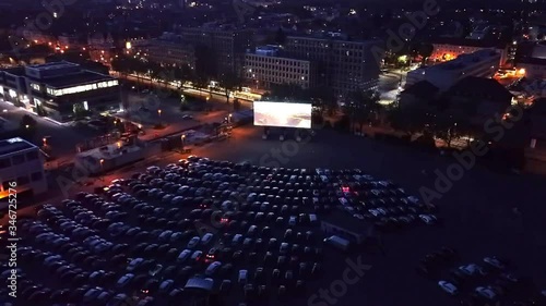 High altitude nighttime drone footage of a drive-in cinema in Corona Crisis times in western Europe with film playing on the big screen photo