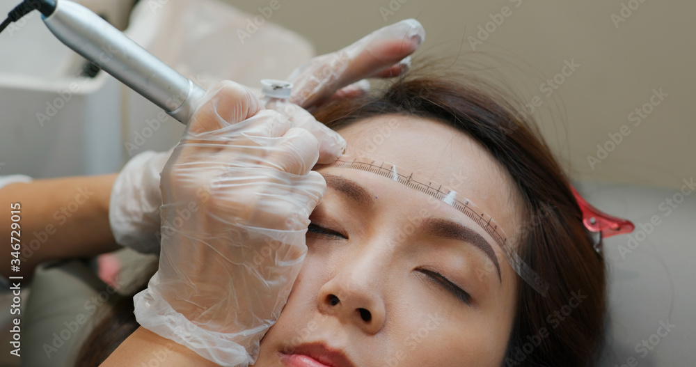 Fototapeta premium Woman undergo eyebrow microblading, permanent makeup