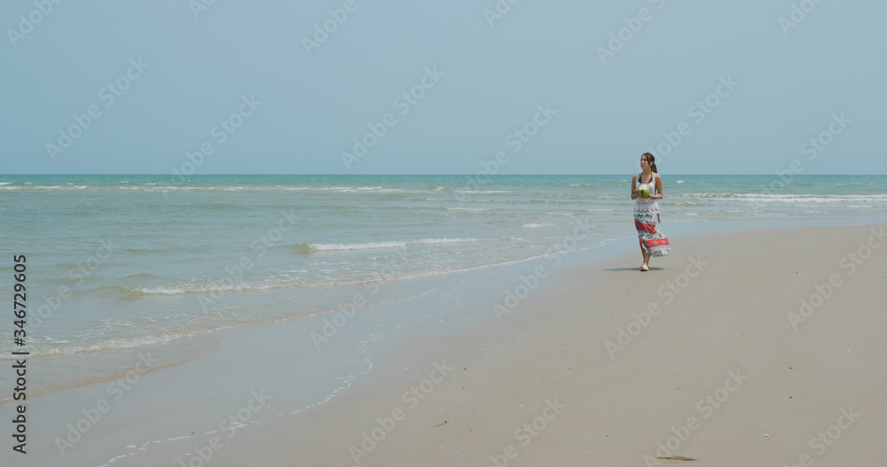 Woman drink of coconut and walk on the beach