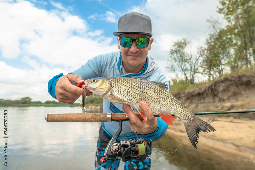 Success fishing. Fisherman with chub fish at wild river Success fishing. Fisherman with chub fish at wild river