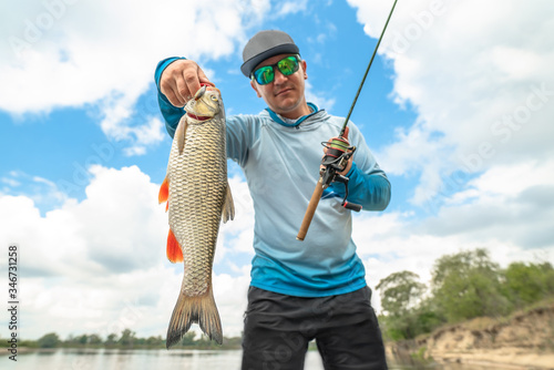 Success fishing. Fisherman with chub fish at wild river
