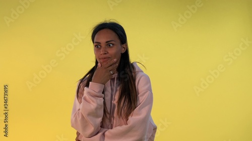 African young woman widely opening her mouth in astonishment on yellow background. She has heard some excellent news.