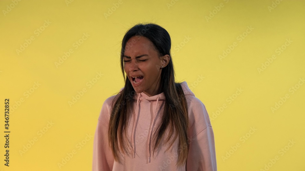 Good-looking african girl screaming loudly. There is yellow background. Good-looking african girl screaming loudly. There is yellow background.