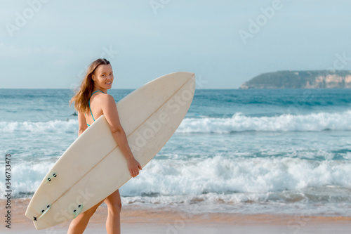 Beautiful sexy surfer girl standing on the beach with surf desk.