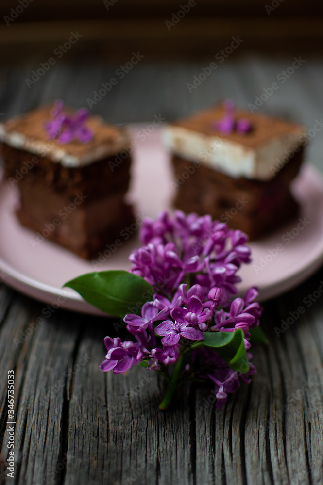 lilac on wooden boards on a background of cake. flowers with sweet pastries on a plate