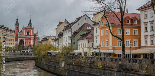 Picturesque buildings along Ljubljanica river on a dull autumn november day. Lazy gray day in Ljubljana, Slovenia, with dirty brown river flowing under the bridge.