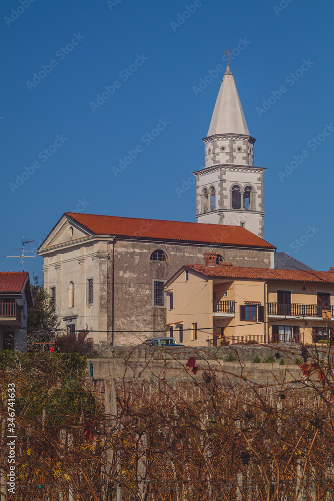 A tyical coastal church in southern Slovenia in the village of Pliskovica on a sunny day in autumn. Grapevine in the foreground. A tyical coastal church in southern Slovenia in the village of Pliskovica on a sunny day in autumn. Grapevine in the foreground.