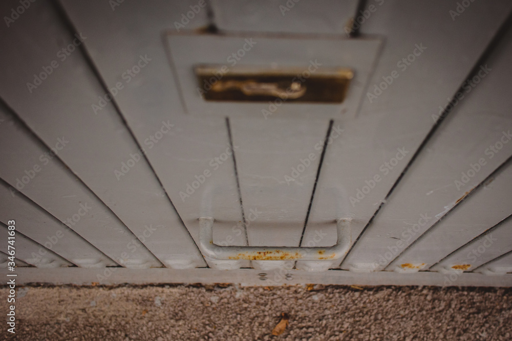 Metal handle on a garage door in grey color. A bit rusty metal holder on a closed gray garage door.