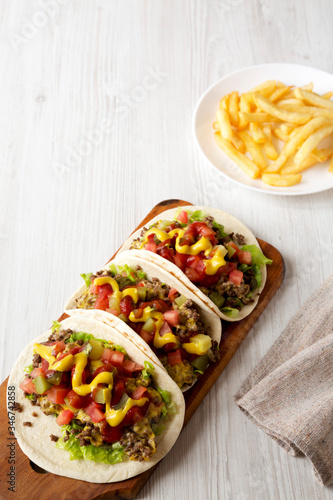Homemade Cheeseburger Tacos and French Fries on a white wooden background, low angle view. Copy space.