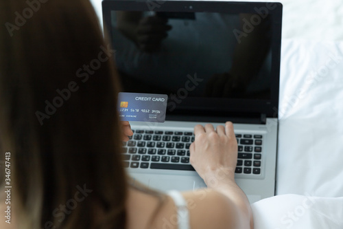 Asian woman paying online. Shopper shopping online with credit card and laptop on bed in home.shopping online concept.