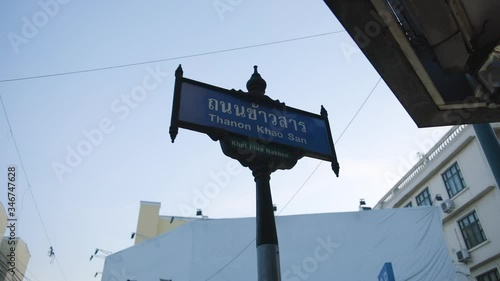 Khaosan Road Sign in the evening at sundown. Close up of Bangkok street sign. Camera focuses on and pivots around the Khaosan road sign, with parallaxing building background against evening blue sky. photo