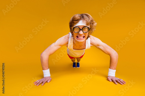 Portrait of his he nice funky motivated mad desperate foxy guy doing work out body building goal squatting endurance isolated over bright vivid shine vibrant yellow color background photo