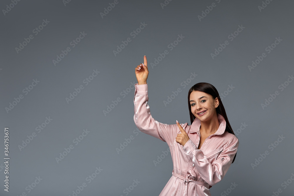 young beautiful woman showing with both hands on side copy space, showing, offering or advertising an object on gray background, copy space. young beautiful woman showing with both hands on side copy space, showing, offering or advertising an object on gray background, copy space.