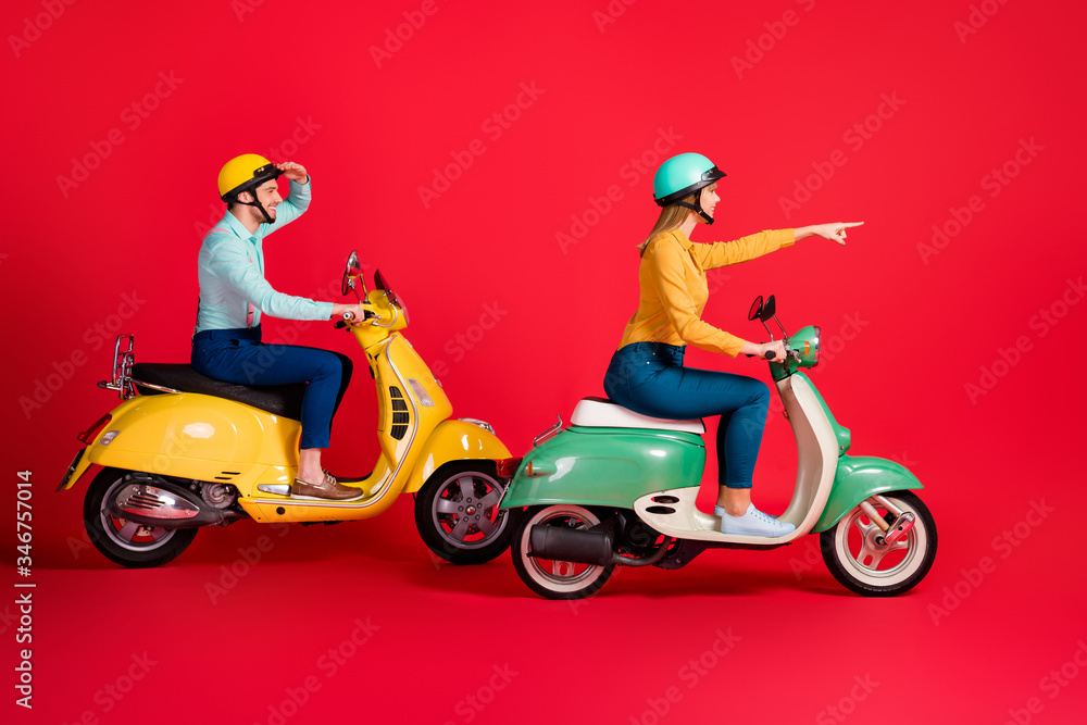Profile side view of her she his he nice attractive cheerful cheery couple tourists riding moped enjoying city tour pointing far away isolated on bright vivid shine vibrant red color background