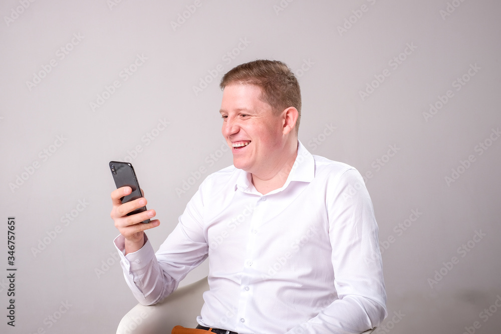 Man in a white shirt on a gray background with a phone Man in a white shirt on a gray background with a phone