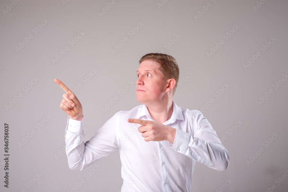 Man in a white shirt on a gray background stands and smiles posing