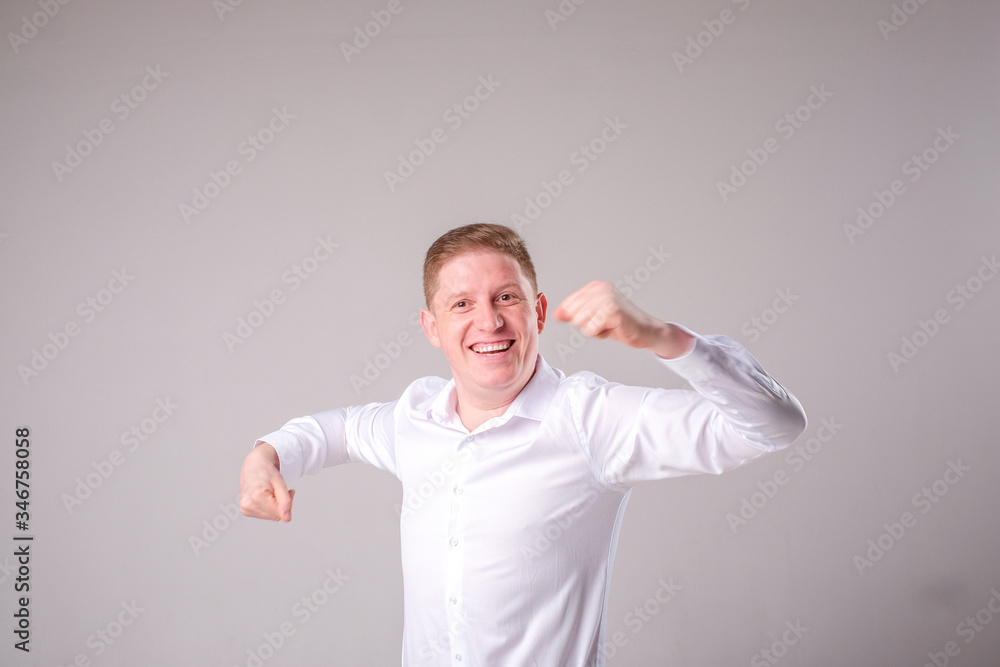 Man in a white shirt on a gray background stands and smiles posing