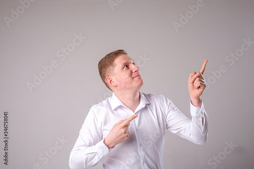 Man in a white shirt on a gray background stands and smiles posing © fotiev