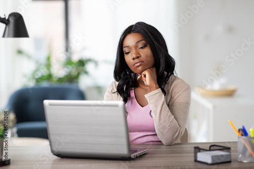 remote job, technology and people concept - african american bored or tired young woman with laptop computer working at home office