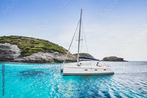 Beautiful beach with sailing boat yacht, Corsica island, France. Yachting, travel and active lifestyle concept 
