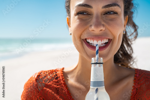 Tela Young happy woman drinking soft drink on beach