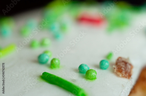 Decorative green confectionery balls decorate the white icing of festive baking. Easter cake close-up, macro shot.