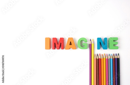  " IMAGINE " Multicolored Wooden Letters with Multicolored Pencil on White Background, Copy Space 
