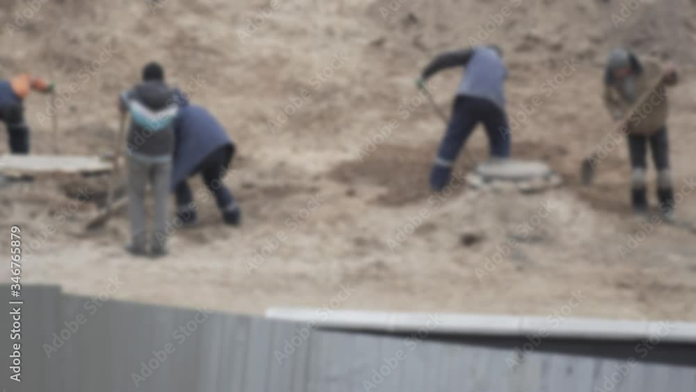 Workers digging shovels at a construction site, industry. Manual labor, blurry, background, copy space Workers digging shovels at a construction site, industry. Manual labor, blurry, background, copy space