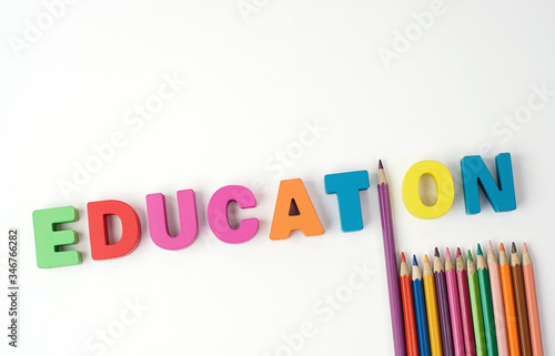 " EDUCATION " Multicolored Wooden Letters with Color Pencil Instead ' I ' Letter on White Background 