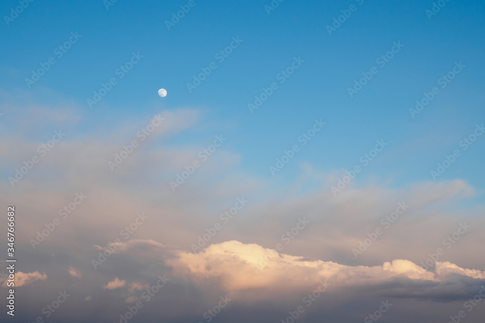 Cirrocumulus and cumulus clouds and full moon on blue sky background Cirrocumulus and cumulus clouds and full moon on blue sky background