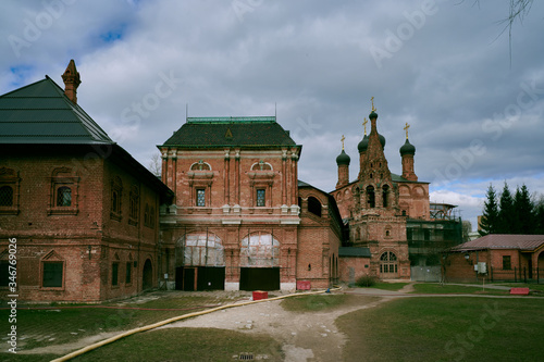 Krutitskoe Podvorye - ancient Russian monument of architecture, cloudy sky, green grass, ancient orthodox church. photo