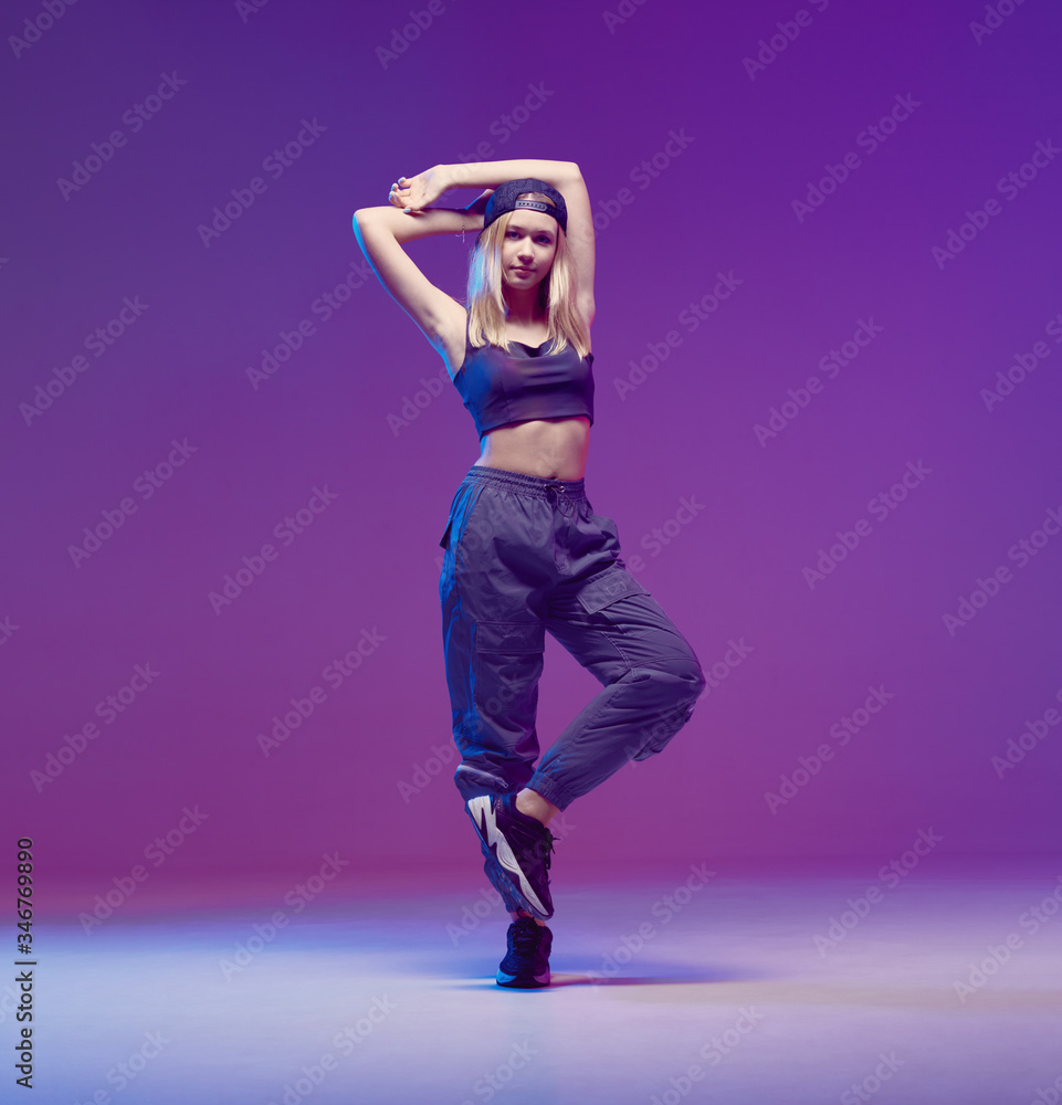 Cute teen girl dancing hip hop in stylish clothes a baseball cap