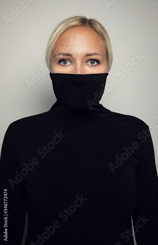 Studio portrait of beautiful elegant woman protect her face in black turtleneck
