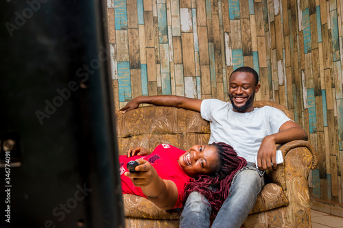 two young African couple watching television celebrating
