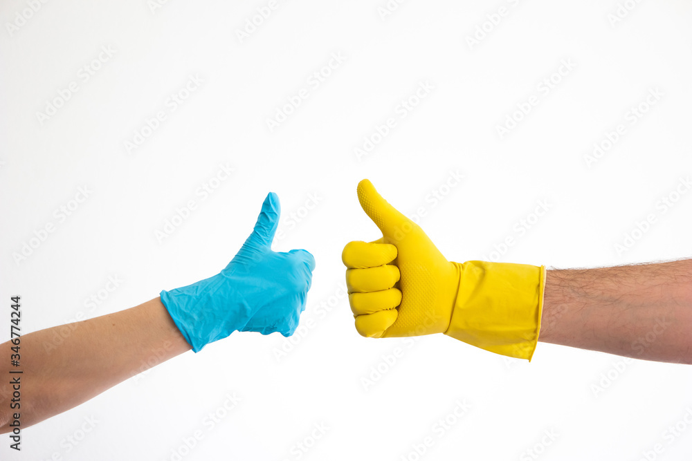 Caucasian woman and man hand in blue and yellow latex gloves doing the thumb up sign isolate on white Caucasian woman and man hand in blue and yellow latex gloves doing the thumb up sign isolate on white