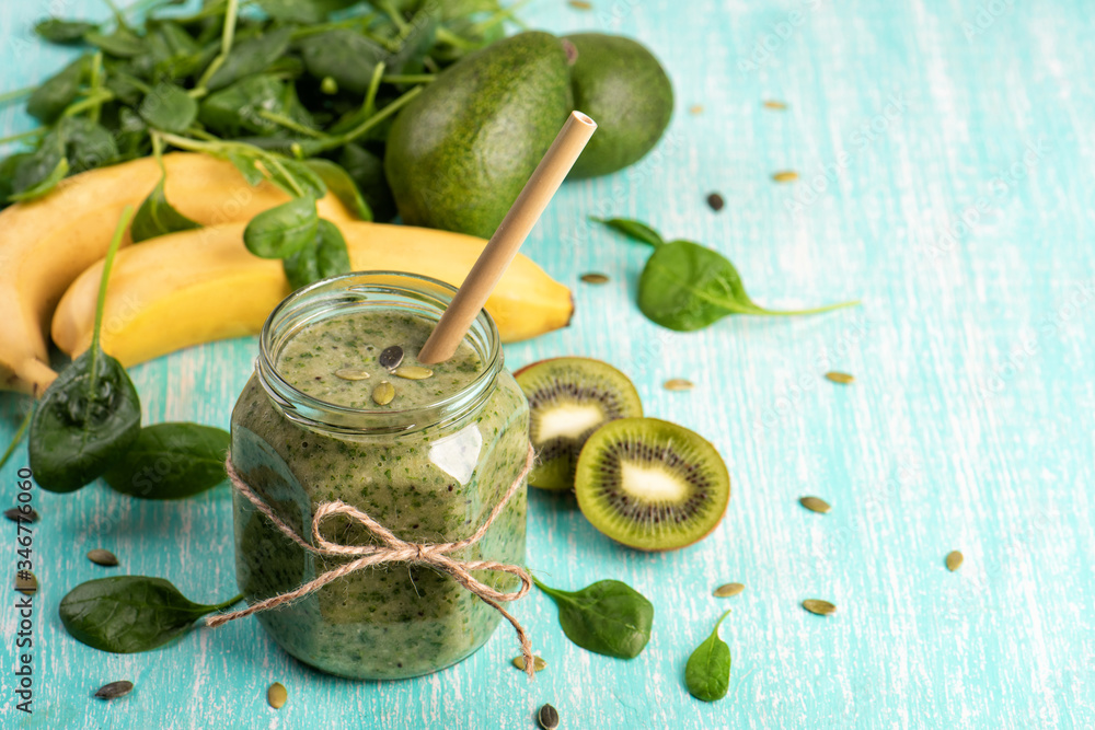 Green detox smoothie in a glass jar with banana, kiwi, spinach on turquoise background. Healthy beverage with vitamins Green detox smoothie in a glass jar with banana, kiwi, spinach on turquoise background. Healthy beverage with vitamins
